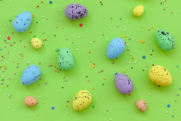 Mehrfarbige Eier mit Konfetti auf grünem Hintergrundhintergrund. Frohe Ostern Konzept.