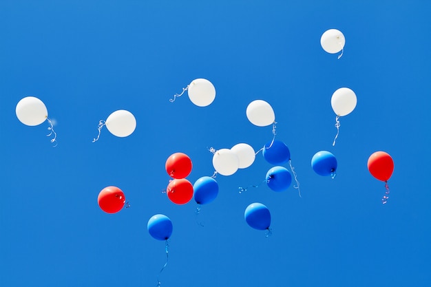 Mehrfarbige Heliumballons, die in den blauen Himmel fliegen