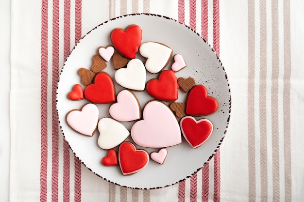 Mehrfarbige herzförmige Kekse zum Valentinstag auf dem Teller. Ansicht von oben.
