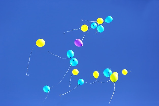 Mehrfarbige Luftballons, die im blauen Himmel fliegen