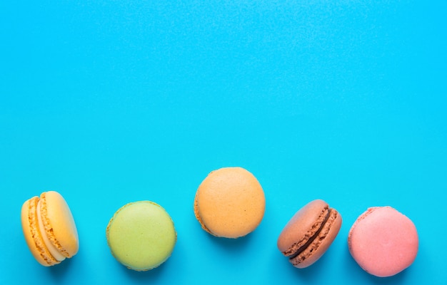 Mehrfarbige Macarons verstreut auf blauem Hintergrund