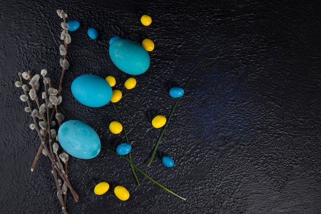 Mehrfarbige Ostereier und Weidenkätzchenzweige auf dunklem strukturiertem Hintergrund