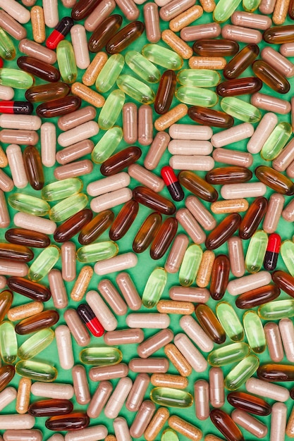 Mehrfarbige Pillen und Kapseln auf grünem Hintergrund