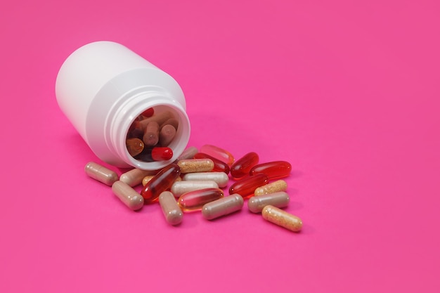 Mehrfarbige Pillen und Kapseln auf rosa Hintergrund