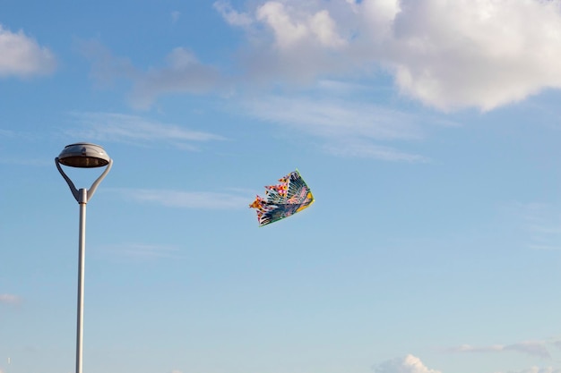 Mehrfarbiger fliegender Drachen am Himmel neben einer Straßenlaterne