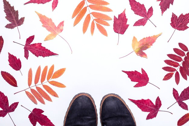 Mehrfarbiger Herbstlaubrahmen und Wildlederstiefel. Hallo, Herbstkonzept.