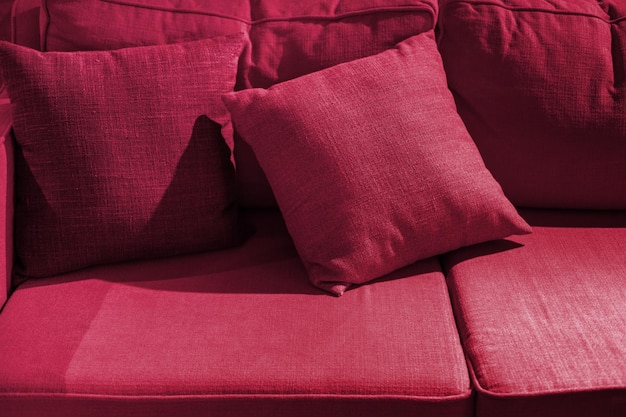 Mehrfarbiges Kissen auf Sofahintergrund. Neue Trendfarbe 2023 PANTONE 18-1750 Viva Magenta