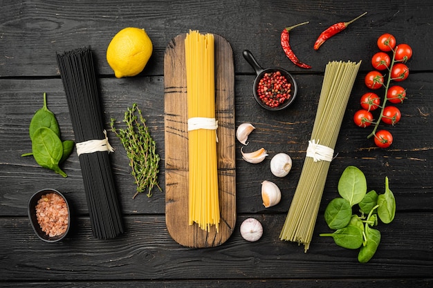 Foto mehrfarbiges pasta-set, auf schwarzem holztischhintergrund, draufsicht flach