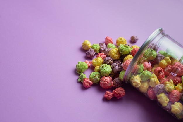 Mehrfarbiges Popcorn mit Fruchtgeschmack in Glasbechern auf rosa Hintergrund. Popcorn mit Bonbonüberzug.