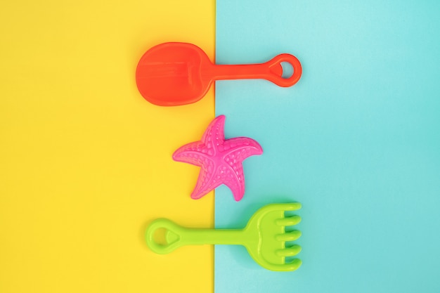 Mehrfarbiges Set Kinderspielzeug für Sommerspiele im Sandkasten oder am Sandstrand auf blauem gelbem Hintergrund.