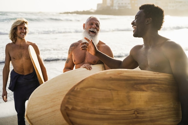 Mehrgenerationen-Surferfreunde, die sich nach der Surfsession am Strand amüsieren Konzentrieren Sie sich auf das Gesicht des älteren Mannes