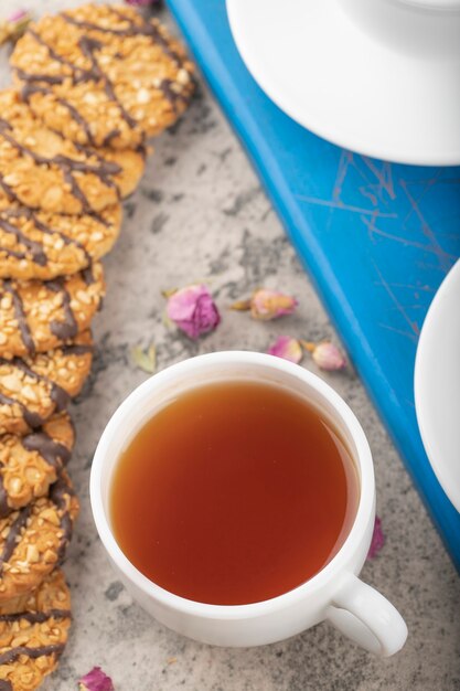 Mehrkornkekse mit Schokolade und Nüssen mit einer Tasse Teeblau.