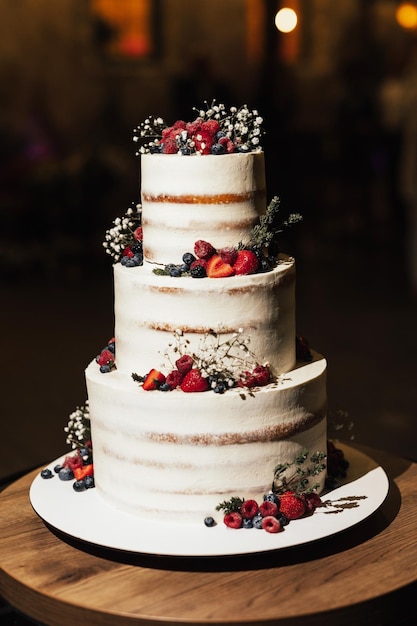 Mehrstöckige Hochzeitstorte mit frischen Beeren und Blumen