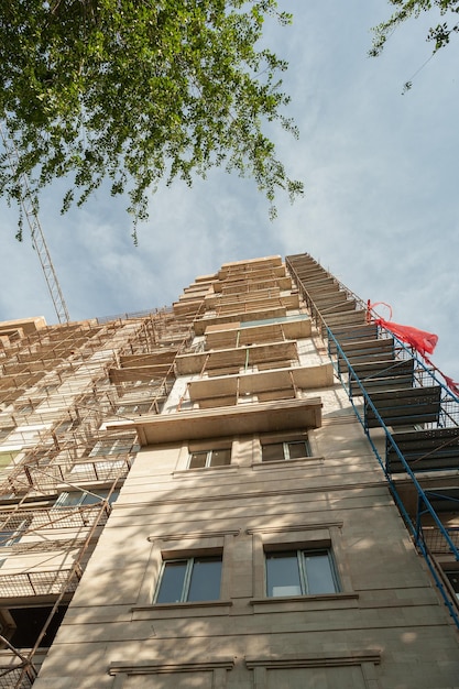 Mehrstöckiges Wohngebäude im Bau und Kran auf blauem Himmel