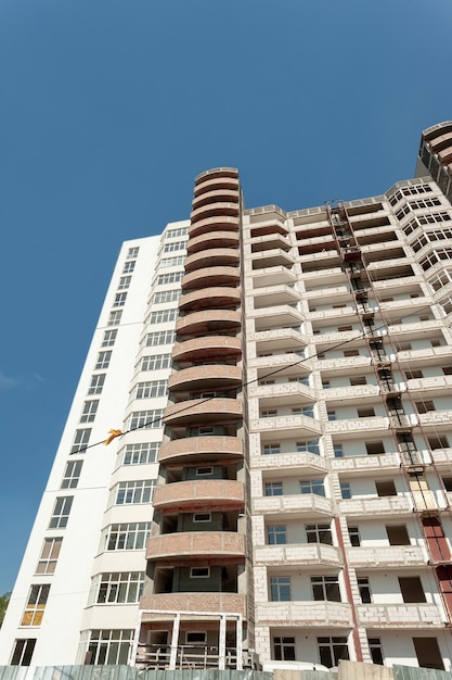 Mehrstöckiges Wohngebäude im Bau und Kran auf einem Hintergrund des blauen Himmels