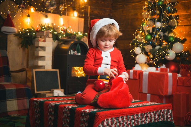 Meia de Natal. Milagre de Natal e sentimentos de ano novo. Um garotinho com roupas quentes sentado e brincando com brinquedos têxteis. Jogos abertos. Primeira memória da infância.