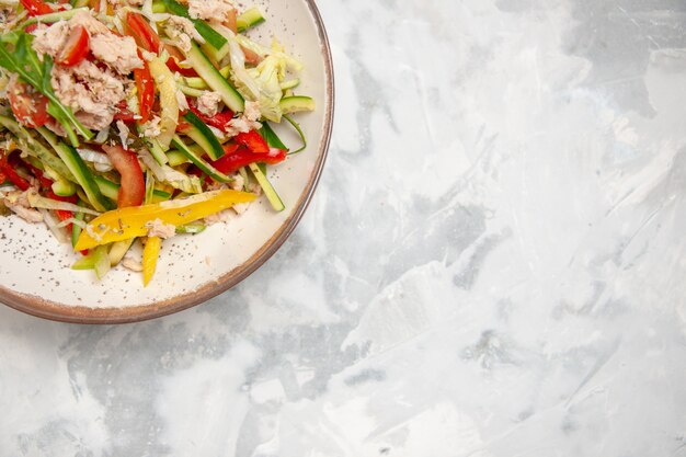 Meia dose de salada de frango com legumes em uma superfície branca manchada com espaço livre