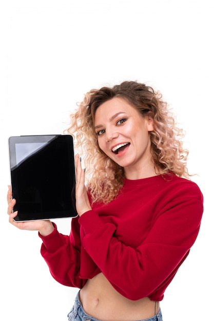 Meia foto de uma garota encantadora com um suéter vermelho com um tablet nas mãos dela, branco isolado