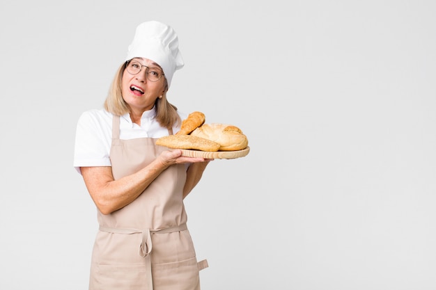 Meia idade, bonito, padeiro, mulher, com, pão, contra, cópia, espaço, parede