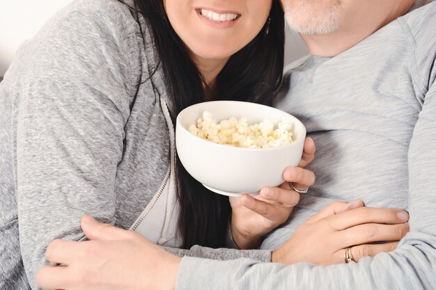 Meia idade, par abraçando, e, comendo pipoca