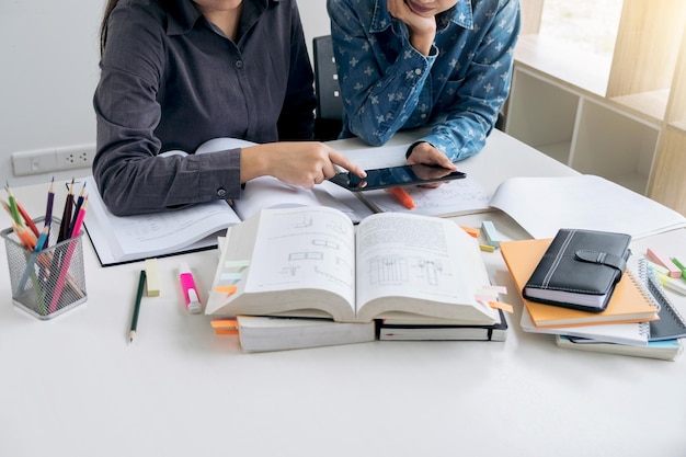 Meia seção de amigos usando tablet digital enquanto estudam na mesa
