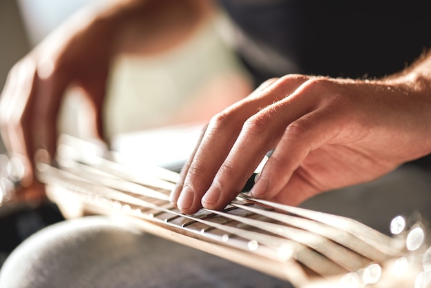 Mein Instrument fühlen...Nahaufnahme männlicher Hände, die Metallsaiten der Gitarre berühren. Musikinstrumente. Musikkonzept. Kreativität