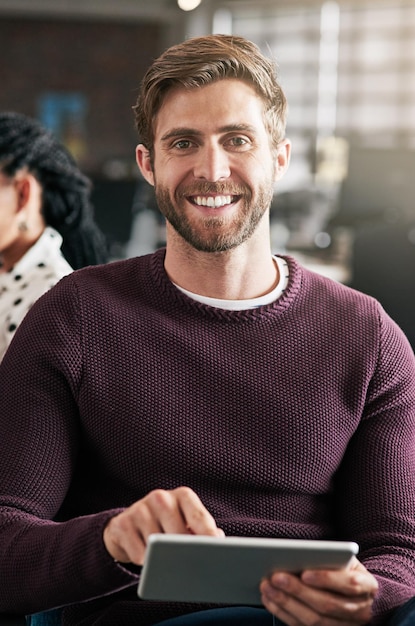 Mein neues Geschäft mit der Online-Community teilen Aufnahme eines jungen Mannes, der in einem Büro ein digitales Tablet verwendet