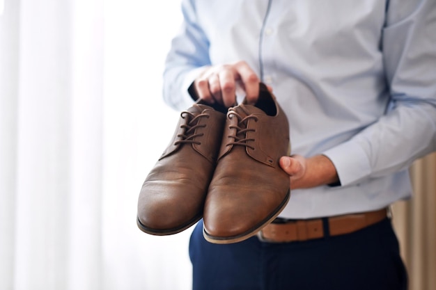 Meine ersten Schritte als verheirateter Mann in dieser Aufnahme eines nicht erkennbaren Bräutigams, der die Schuhe hält, die er an seinem Hochzeitstag in einer Umkleidekabine tragen wird