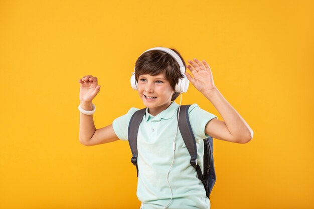 Meine Lieblingsbeschäftigung. Zufriedener sportlicher Junge, der seine Schultasche trägt und Musik hört