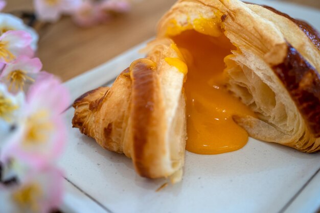 meio corte de croissant de lava de creme de ovo salgado no prato na mesa de madeira