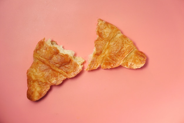 Meio croissant simples em fundo rosa, de cima para baixo