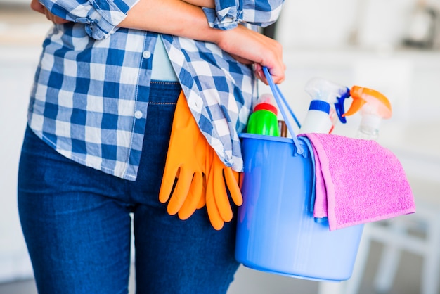 Foto meio da mão da mulher segurando equipamentos de limpeza no balde