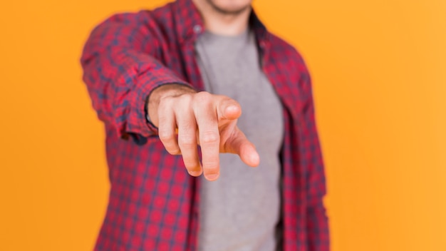 Meio de um homem apontando o dedo para a câmera contra um pano de fundo laranja