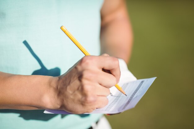 Meio do jogador de golfe com cartão de pontuação