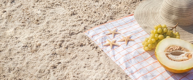 Meio melão, uvas, estrelas do mar na praia. Vista superior, configuração plana. Bandeira.