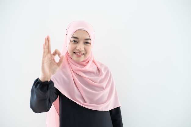 Meio retrato do comprimento da bela jovem muçulmana asiática vestindo trajes de negócios e hijab com poses misturadas e gestos isolados na parede cinza. Apropriado para a tecnologia, tema de finanças de negócios.