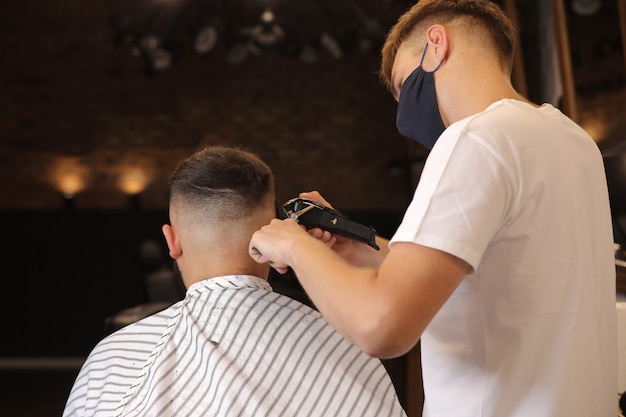 Meister, der einem Mann in einem Friseurladen die Haare schneidet