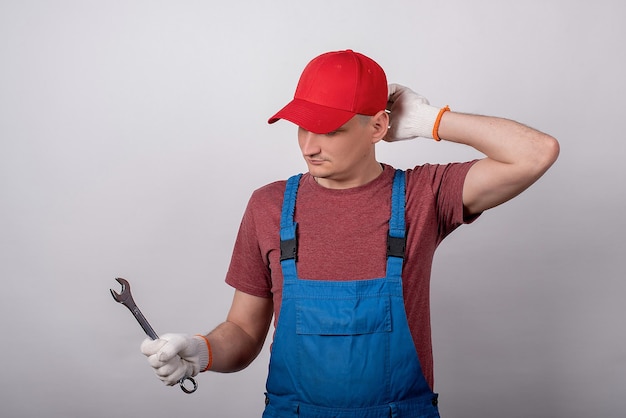 Meister mit einem Schraubenschlüssel auf weißem Hintergrund in einer Arbeitsuniform mit einem Lächeln handymanxA