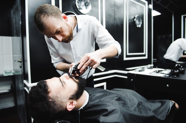 Meister schneidet Haare und Bart von Männern im Friseursalon, Friseur