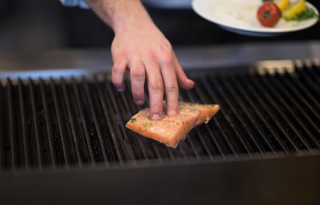 Meisterkoch kocht gegrillten Lachsfisch mit Kartoffeln in einer Restaurantküche