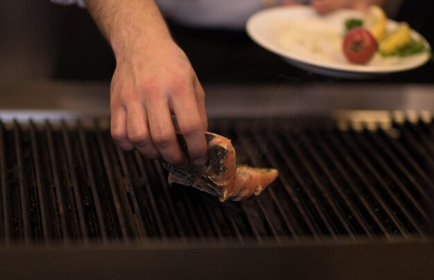 Meisterkoch kocht gegrillten Lachsfisch mit Kartoffeln in einer Restaurantküche