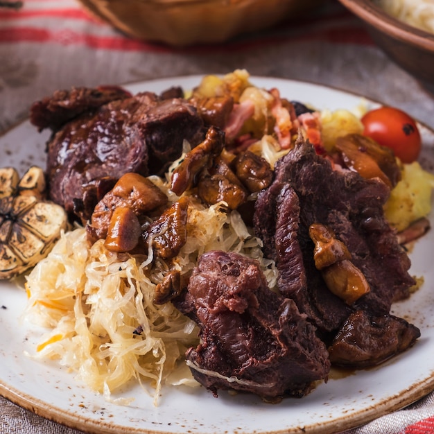 Mejillas de ternera con patata, chucrut y champiñones.