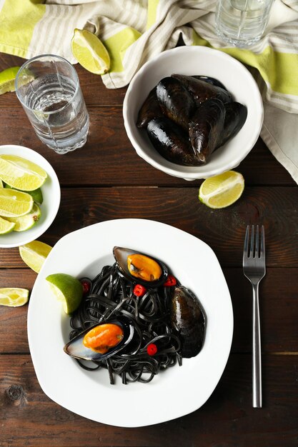 Mejillón de pasta cocida y lima sobre fondo de madera marrón