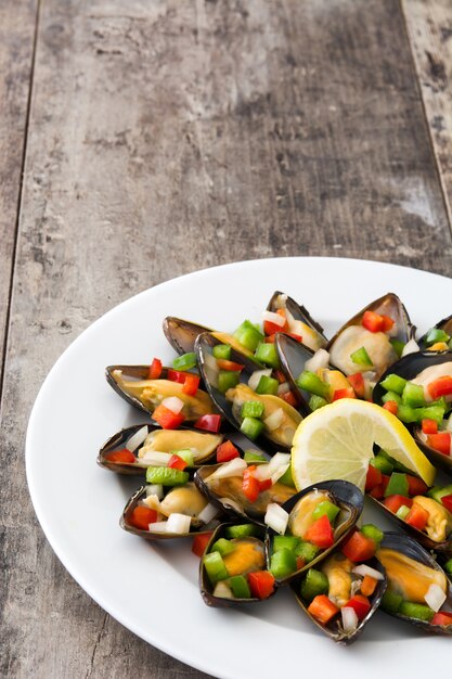 Mejillones al vapor con pimientos y cebolla en mesa de madera copyspace