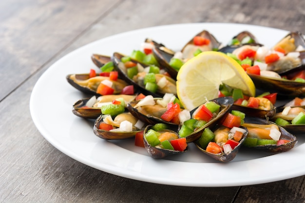 Mejillones al vapor con pimientos y cebolla en mesa de madera