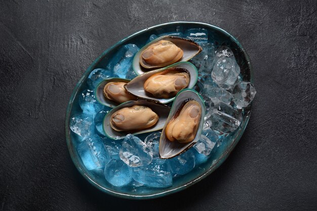 Mejillones crudos de mariscos en un plato sobre cubitos de hielo