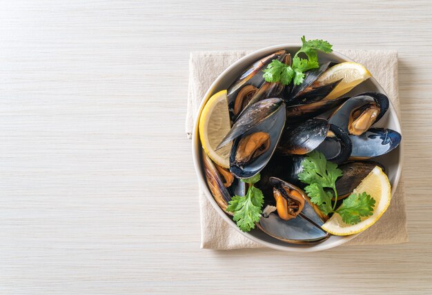 mejillones frescos con hierbas en un bol con limón