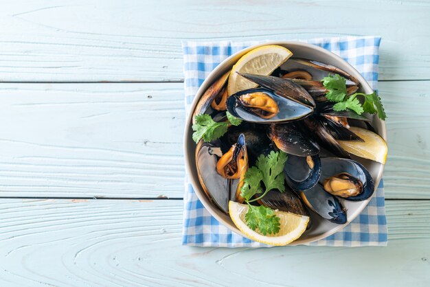 mejillones frescos con hierbas en un bol con limón