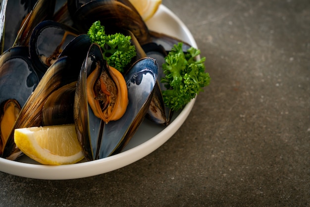 mejillones frescos con hierbas en un bol con limón