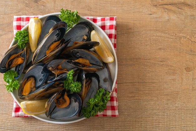 mejillones frescos con hierbas en un bol con limón